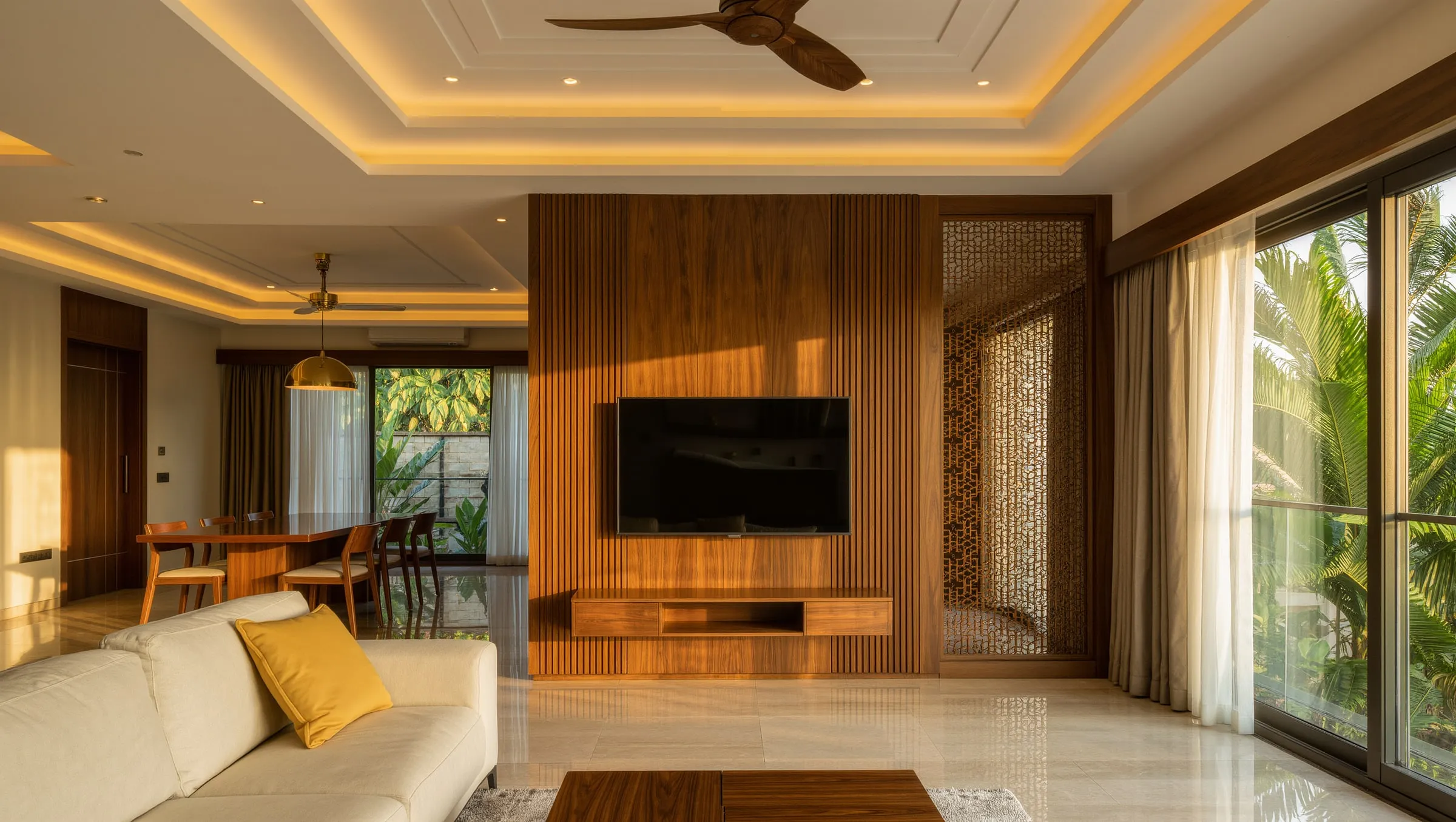 Living room with teak slat TV wall, jaali screen and cove-lit false ceiling