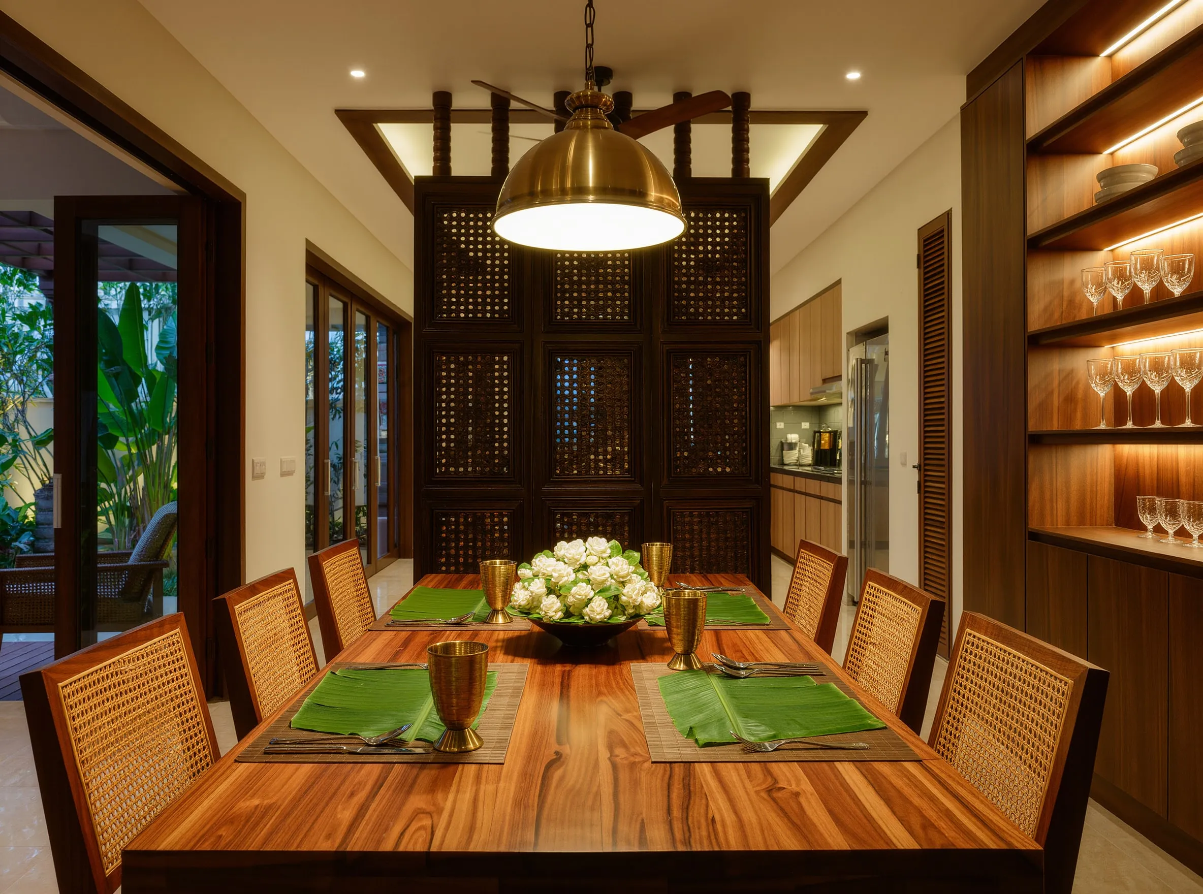Warm family dining space with teak table, brass pendant and jaali screen