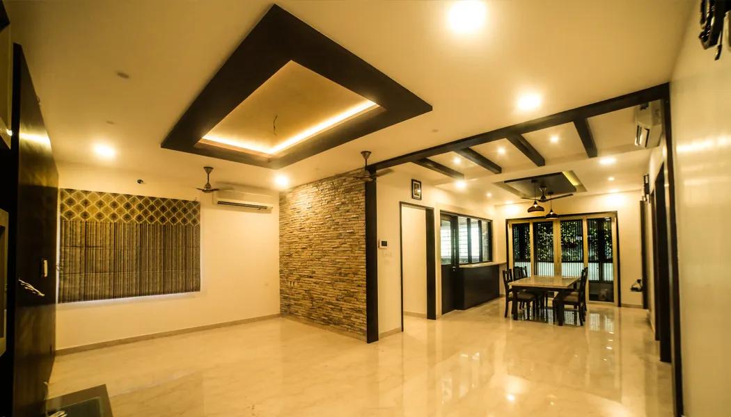 Living and dining room with layered false ceiling and stone feature wall by Ploceus Designs, Chennai